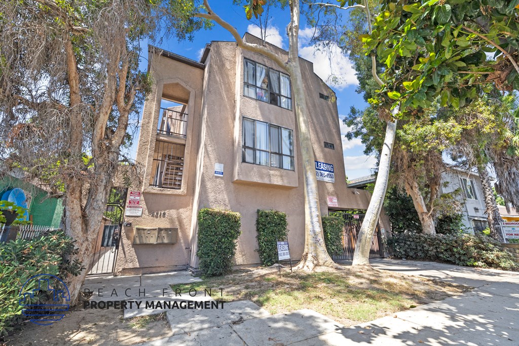 an apartment building with trees and a sidewalk