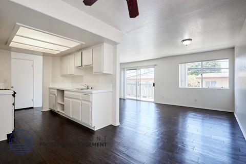 A spacious kitchen with white cabinets and a wooden floor.