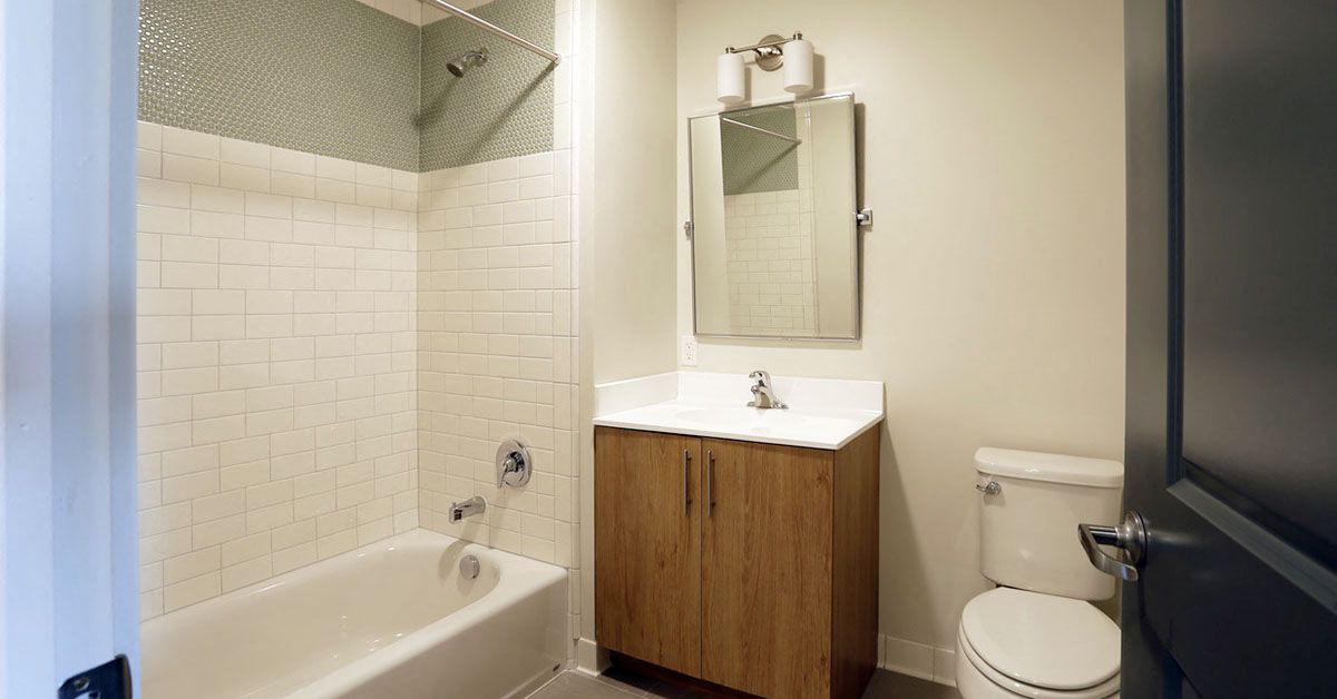 Bathroom with wooden cabinet, white walls and white tile shower