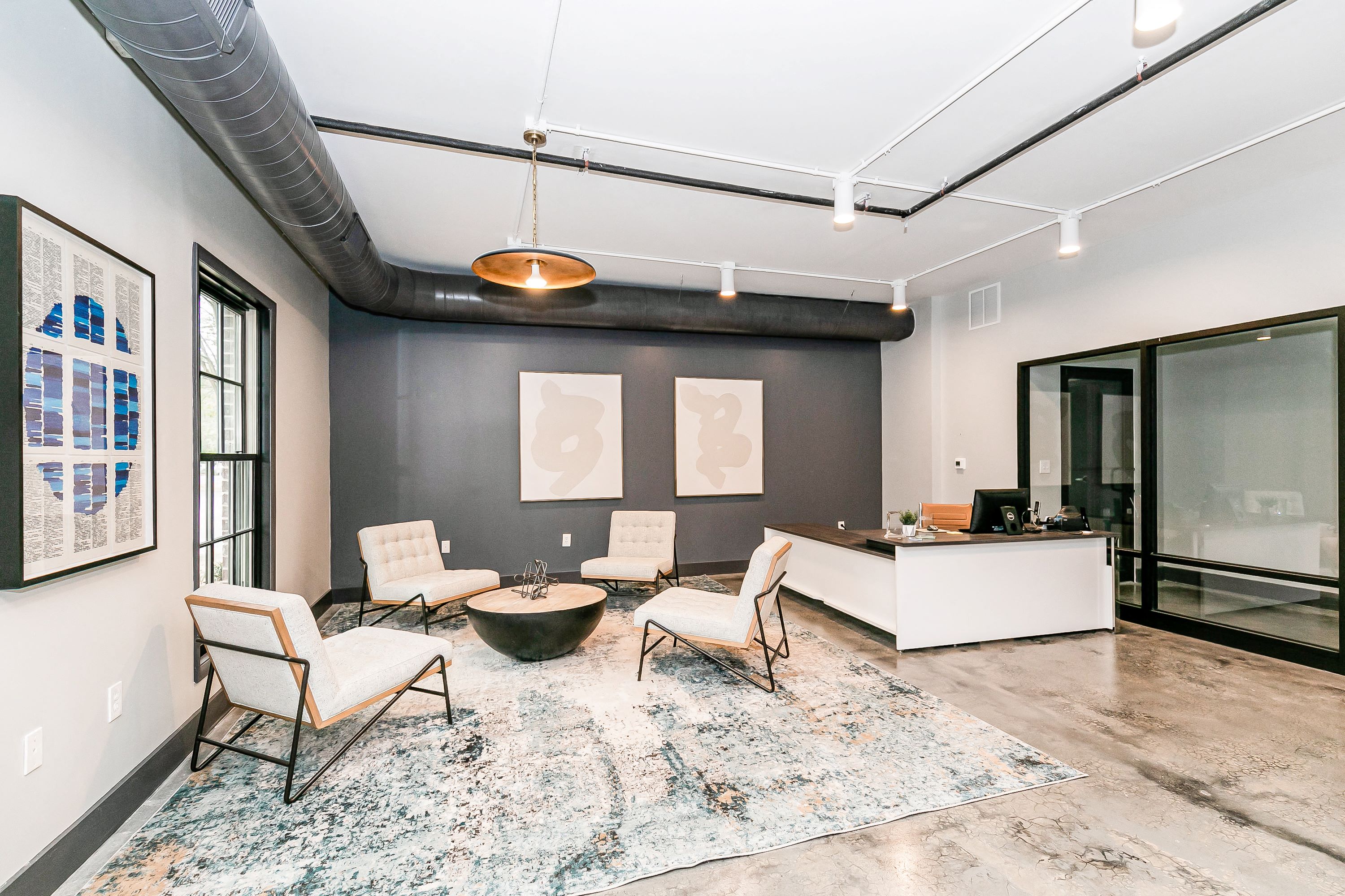 a living room with chairs and a desk and a large window