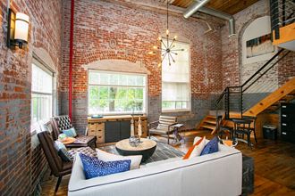 the living room of an industrial loft with a couch and chairs and a spiral staircase