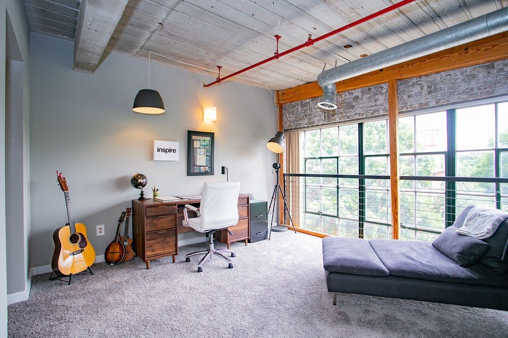 a living room with a couch and a desk and a guitar