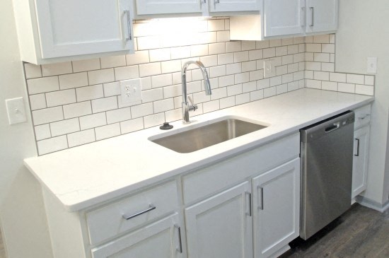an empty kitchen with white cabinets and a sink