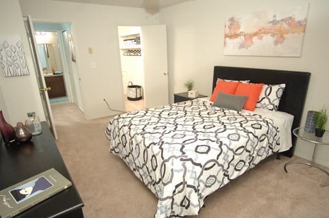 a bedroom with a black and white comforter and orange pillows