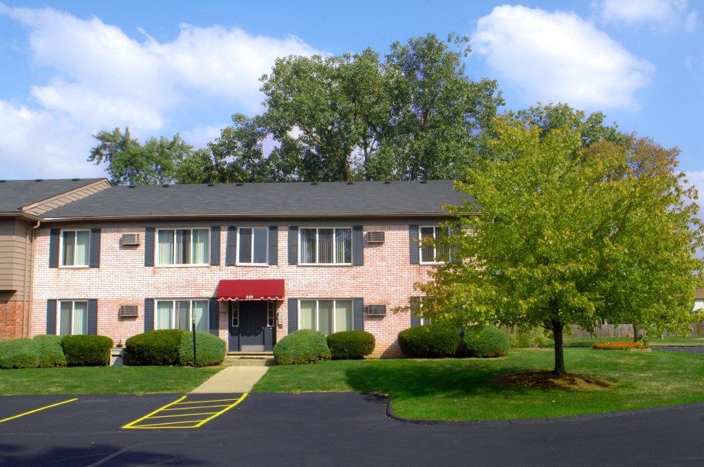 a brick apartment building with a red awning and a tree