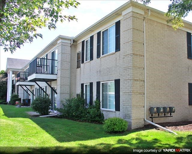 a brick building with a balcony and a grass yard