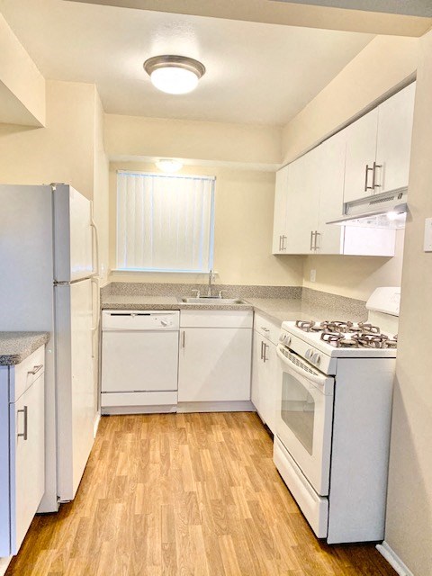an empty kitchen with white appliances and white cabinets