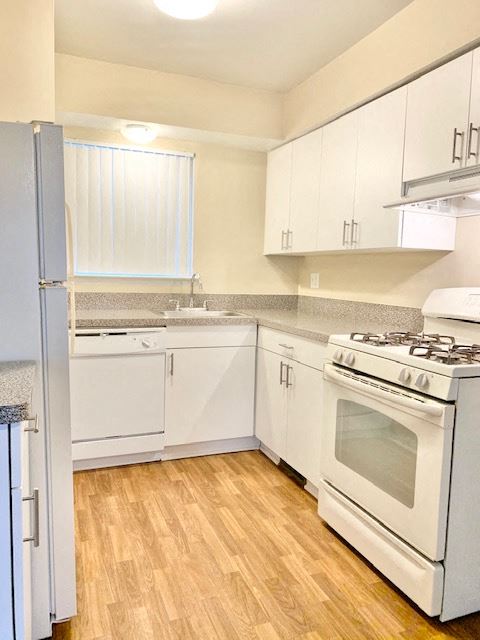 an empty kitchen with white appliances and white cabinets