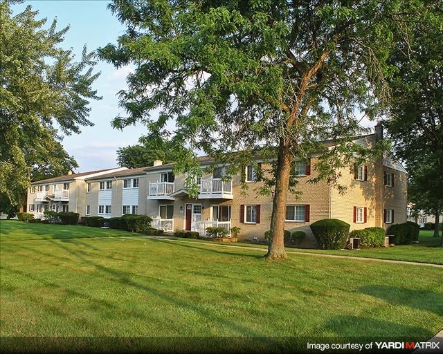 a row of apartment buildings on a green lawn