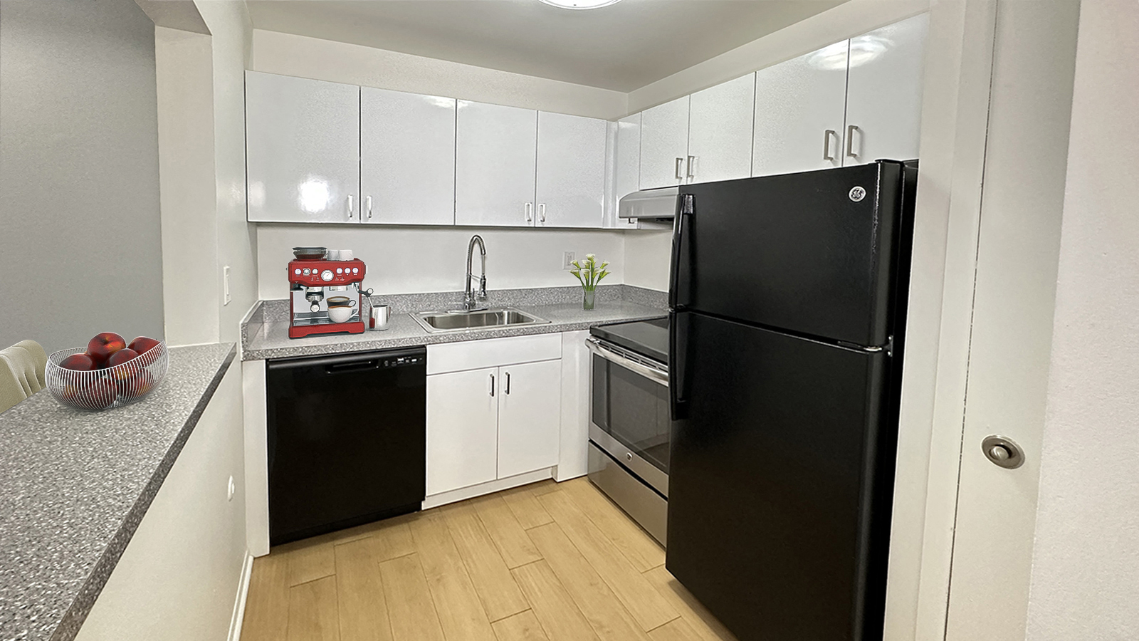 A black refrigerator stands in a kitchen with white cabinets and a granite counter.