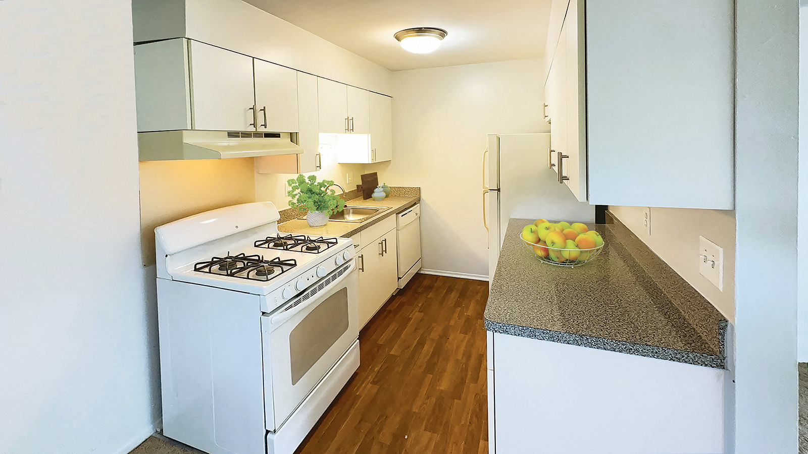 A kitchen with a white stove and a bowl of fruit on the counter.
