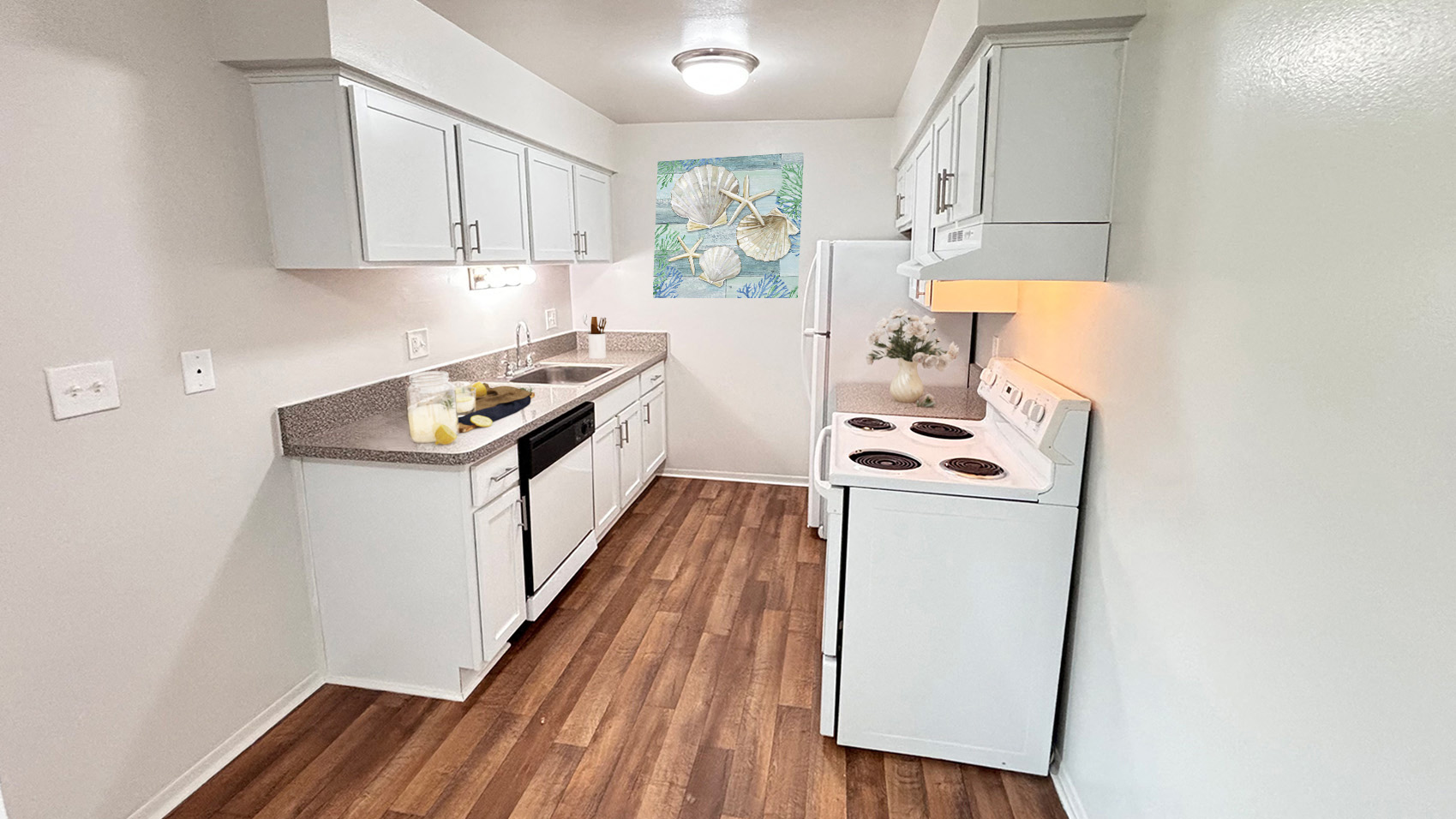 A small kitchen with white appliances and wooden floors.