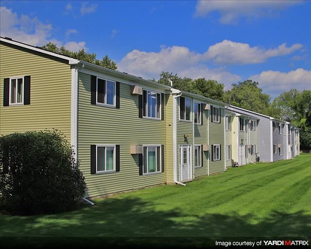 a row of apartment buildings on a green lawn
