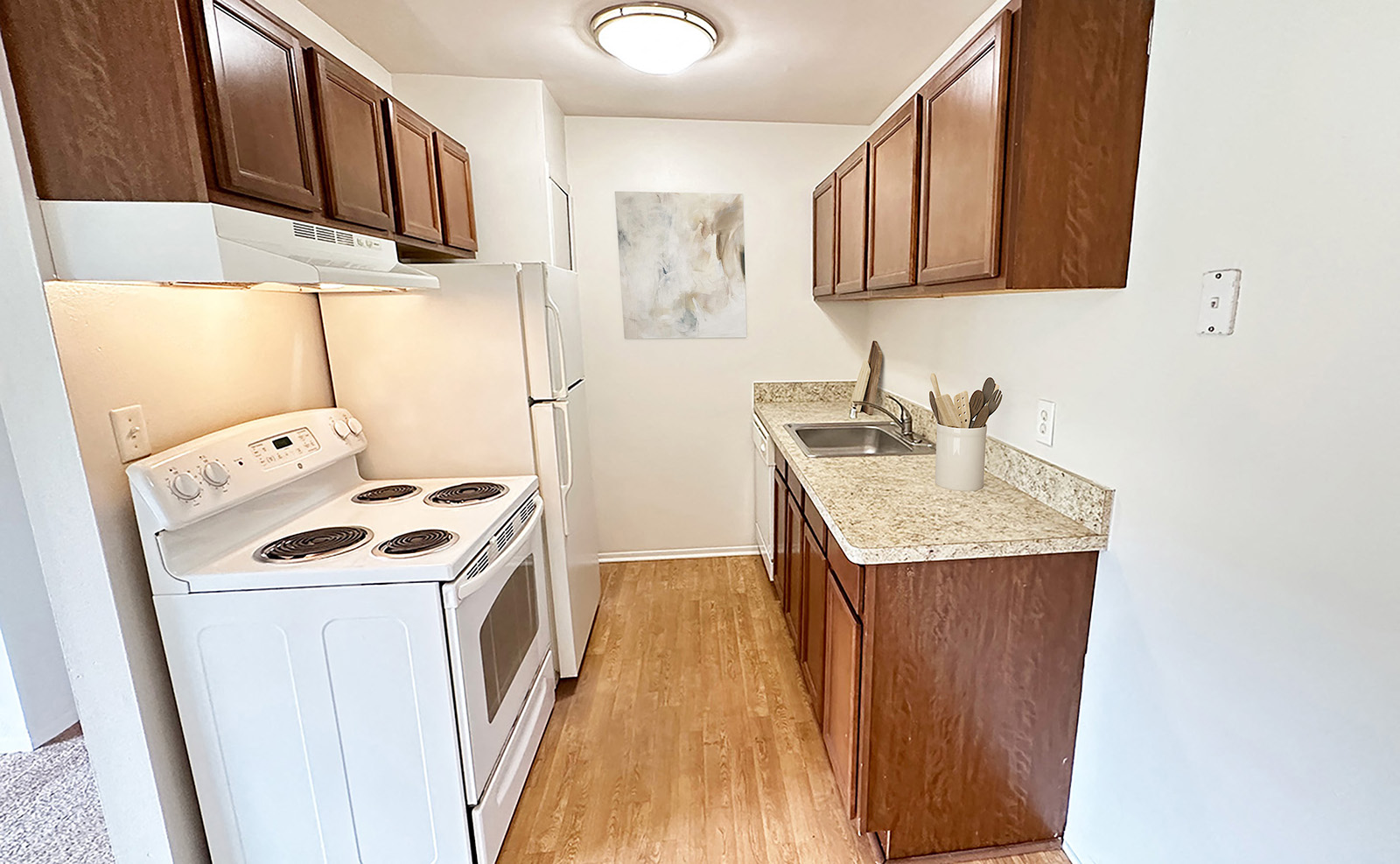 A kitchen with white appliances and wooden cabinets.