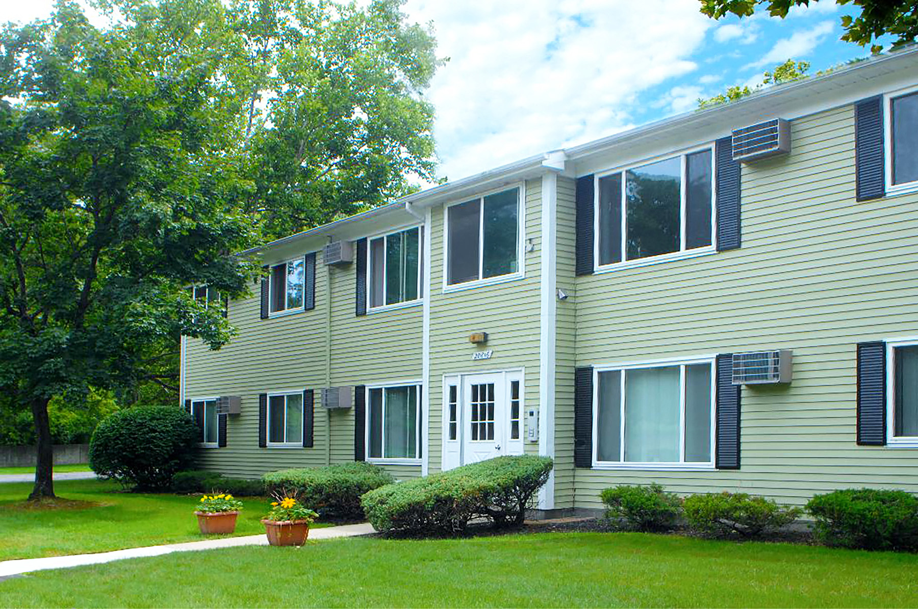 A building with a white door and windows with black shutters.