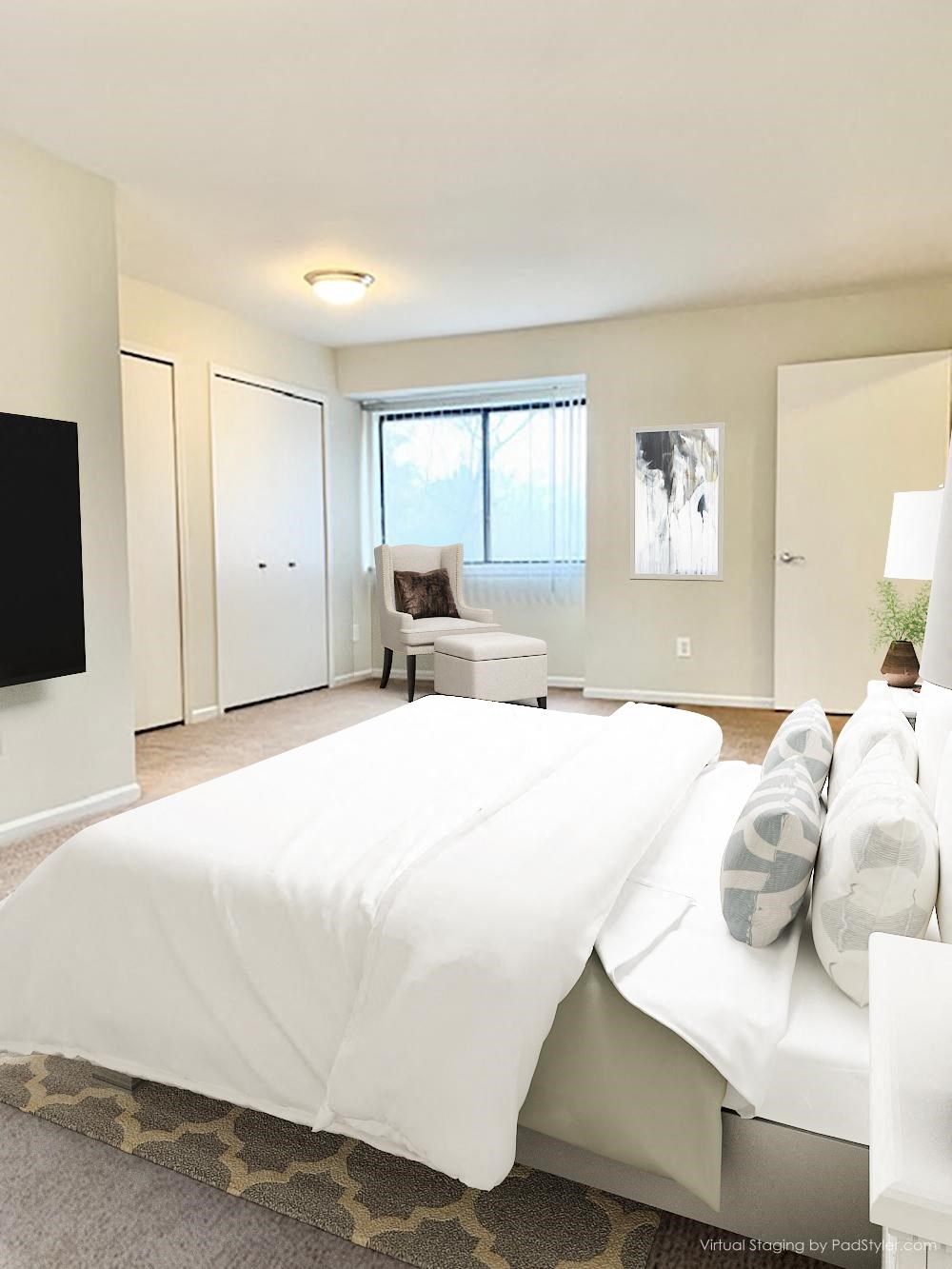 a white bedroom with a large bed and a tv