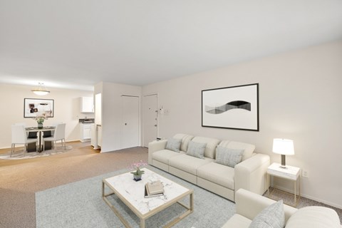 A living room with a white couch, a coffee table, and a painting on the wall.