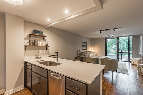 a kitchen with a sink and a counter next to a living room