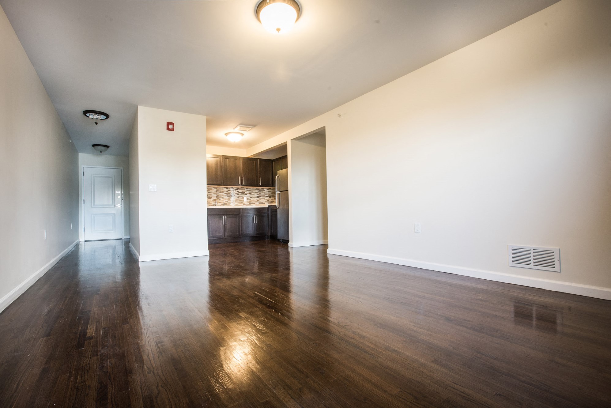 Living room with partially open layout, darker hardwood floors and white walls