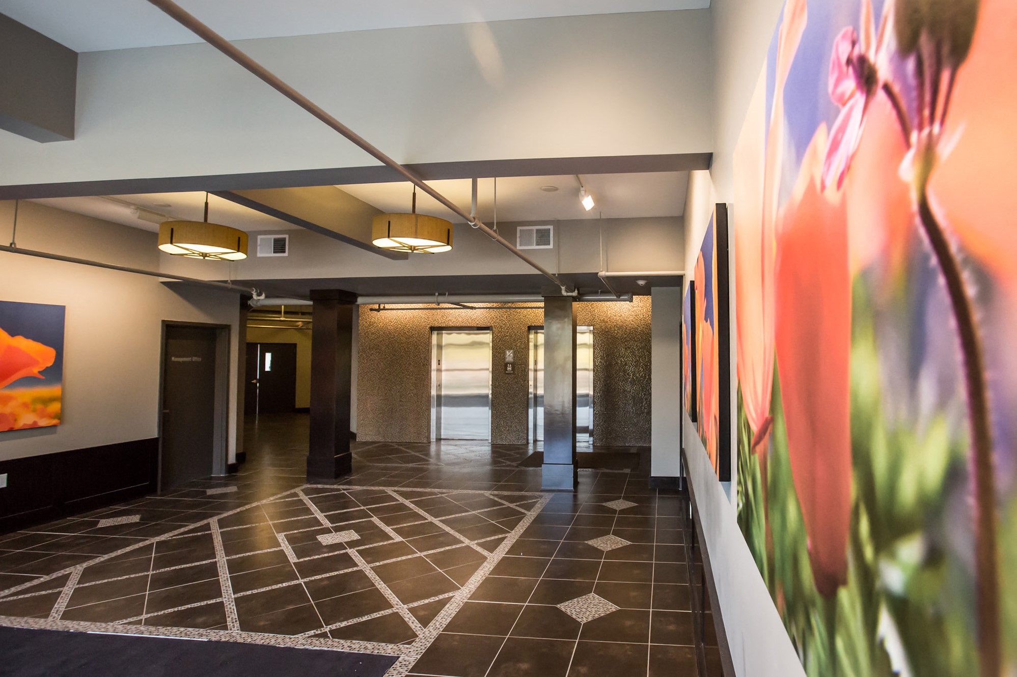 Lobby with black and white designed tile floors and colorful paintings on the wall
