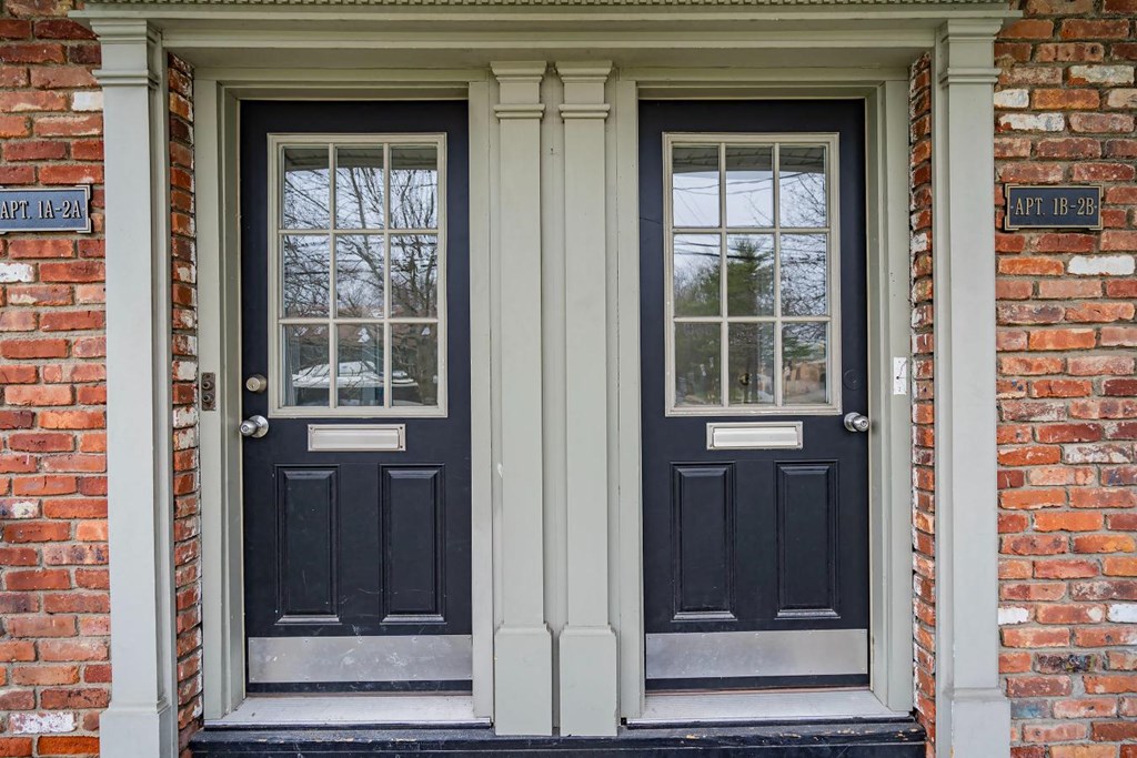 the front door of a brick house with black doors