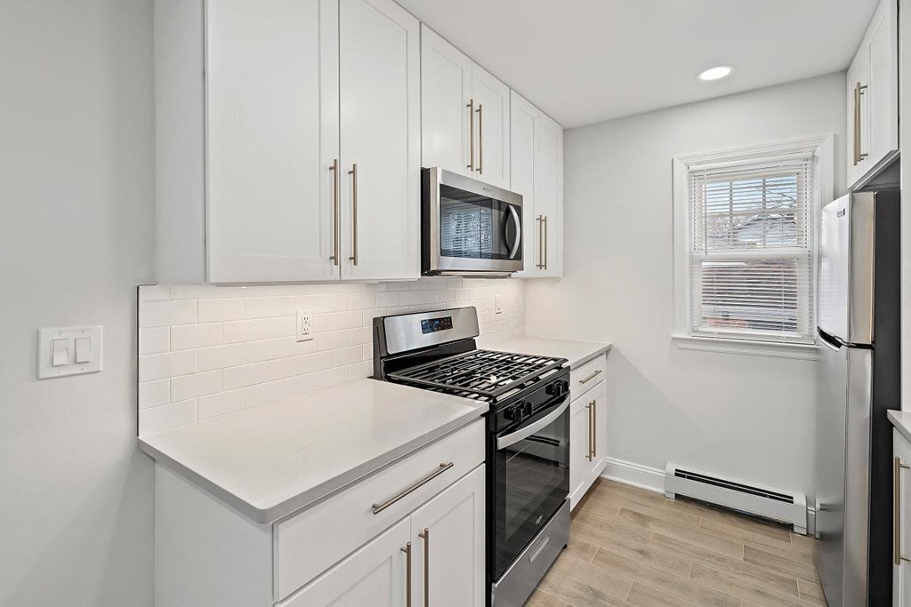 a kitchen with white cabinets and a stove and a microwave