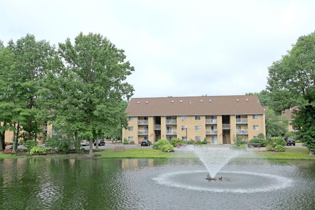 a fountain in the middle of a lake in front of an apartment building
