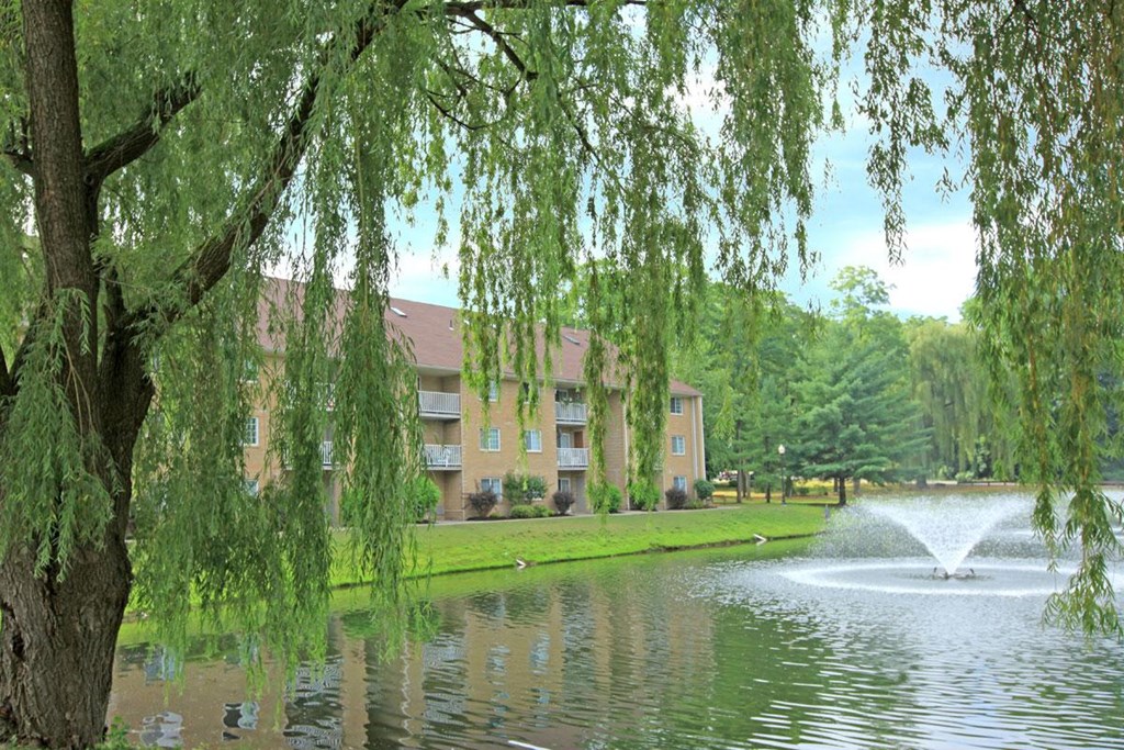 a pond with a fountain in front of an apartment building
