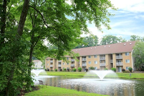 a fountain in a pond in front of an apartment building