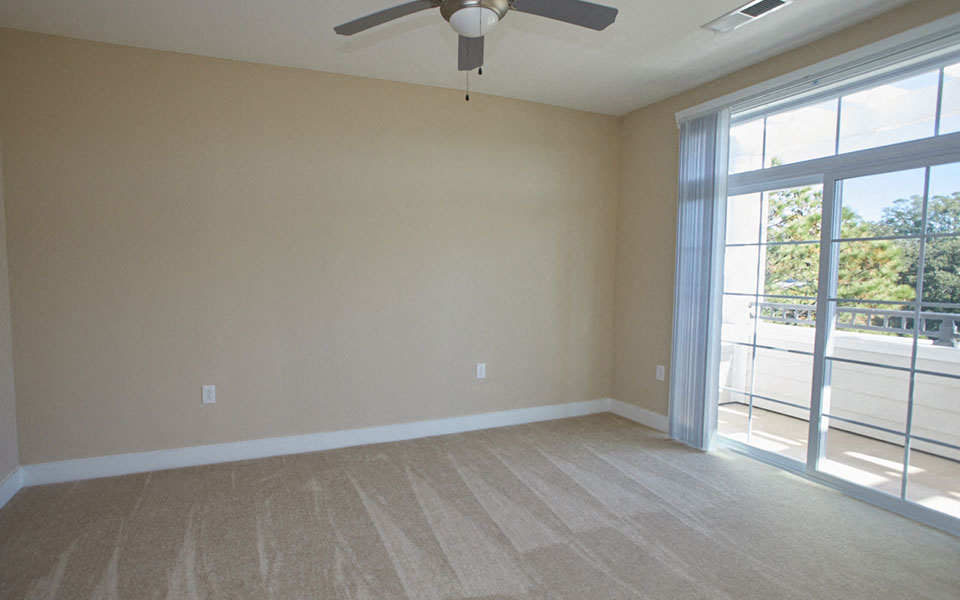 an empty living room with a ceiling fan and a sliding glass door