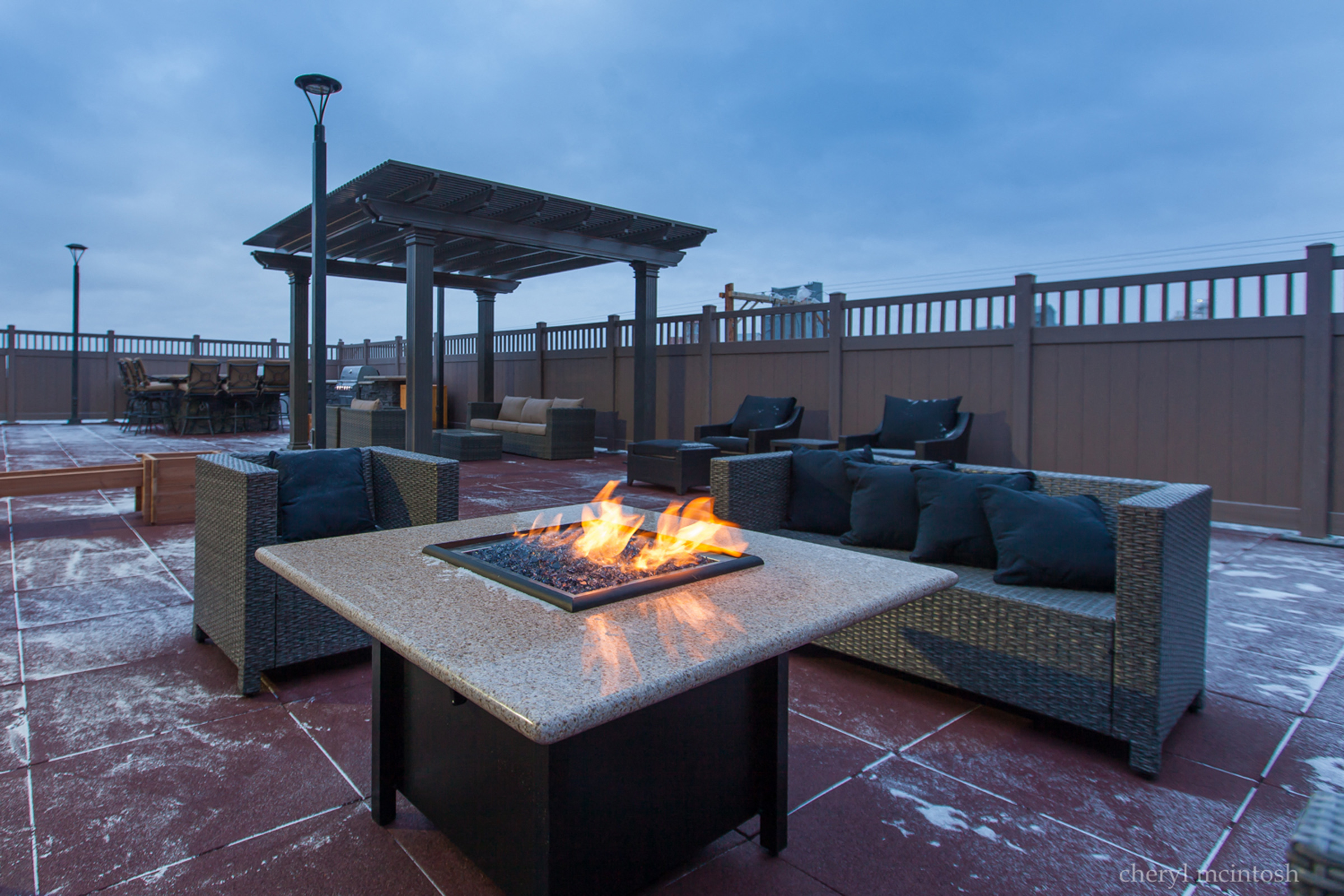 a patio with a fire pit and furniture on a rooftop