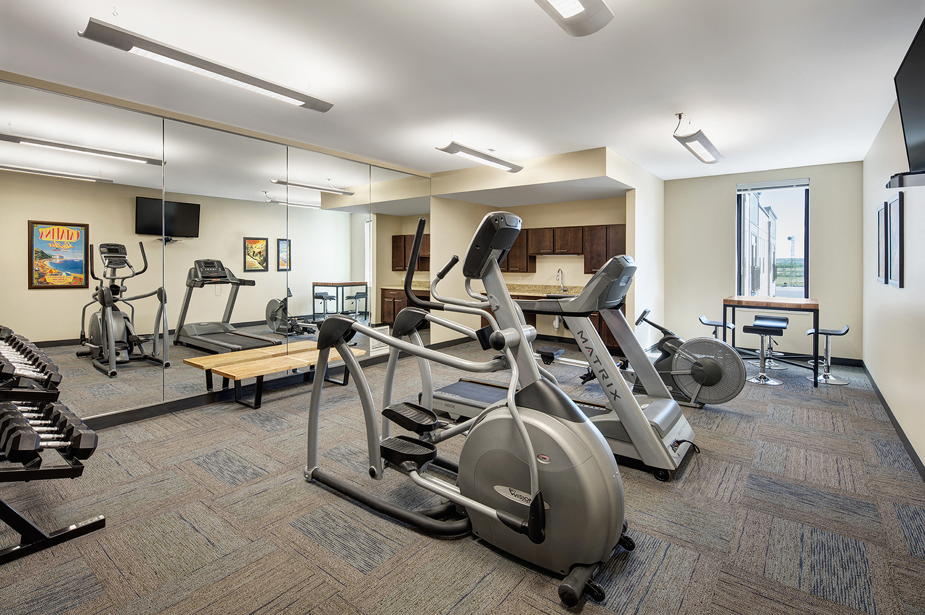 a gym with treadmills and other exercise equipment in a room with a window