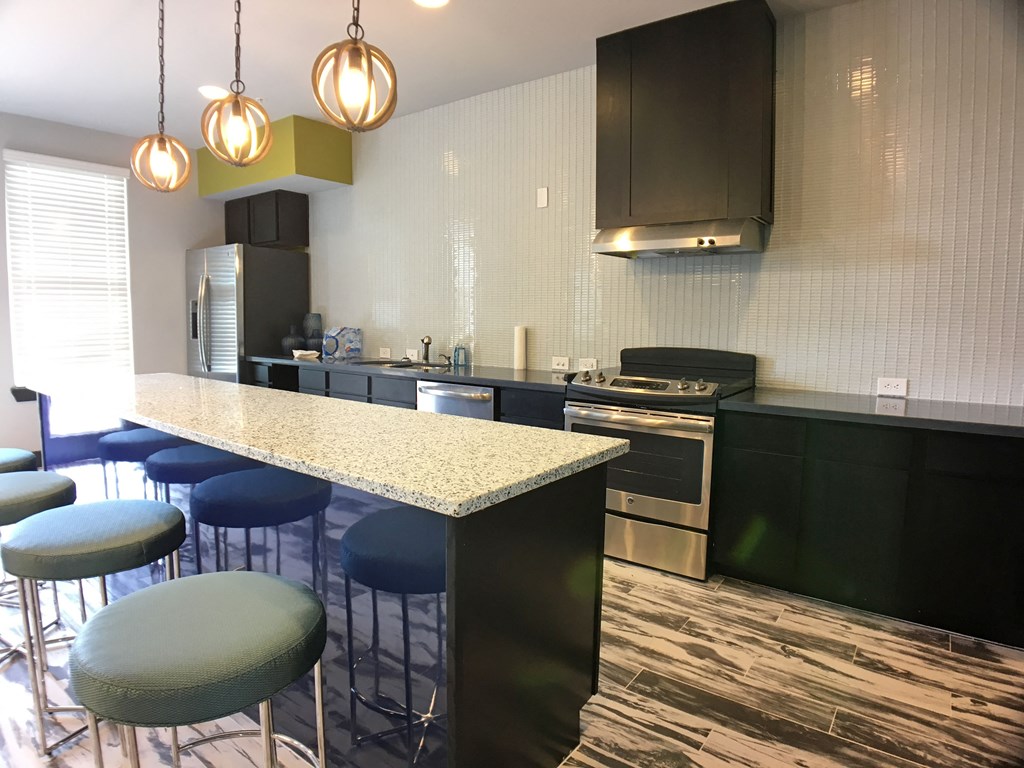 a kitchen with a long island with chairs and a counter top