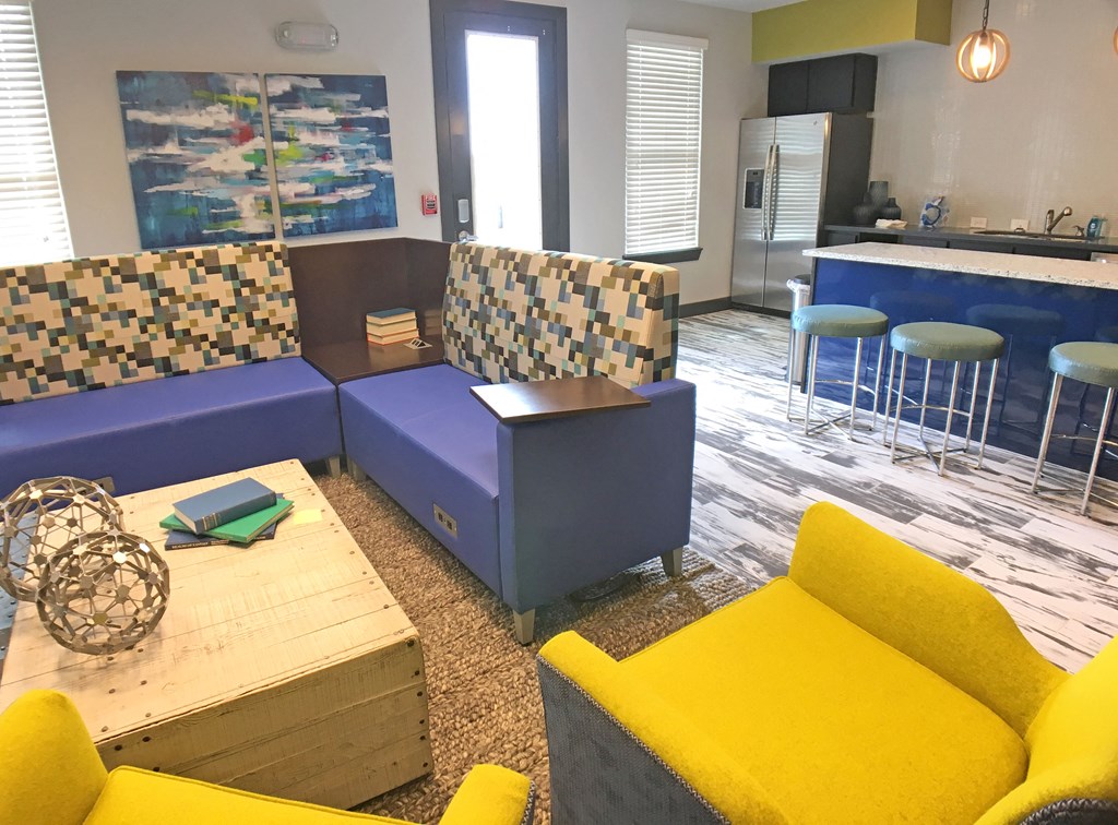a living room with blue and yellow furniture and a kitchen