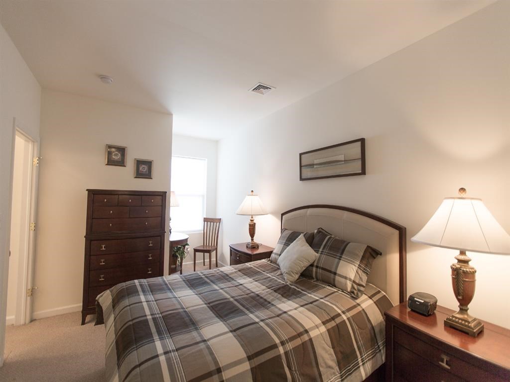 a bedroom with a bed and a dresser and a window