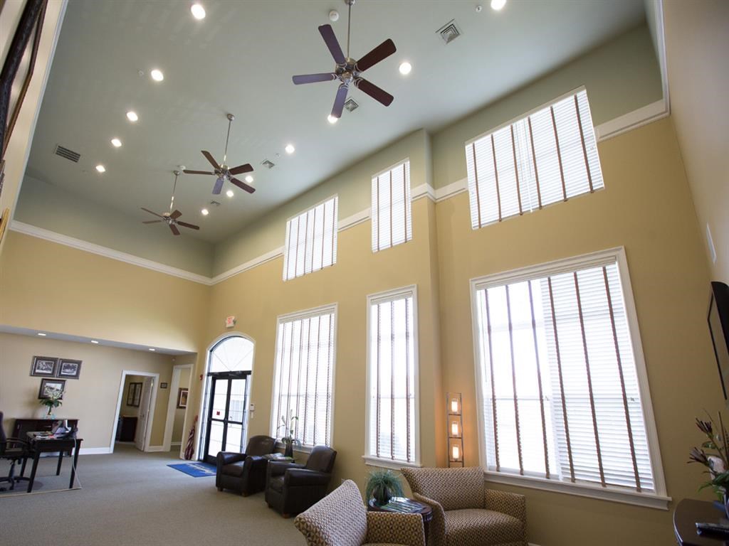 a large living room with large windows and a ceiling fan