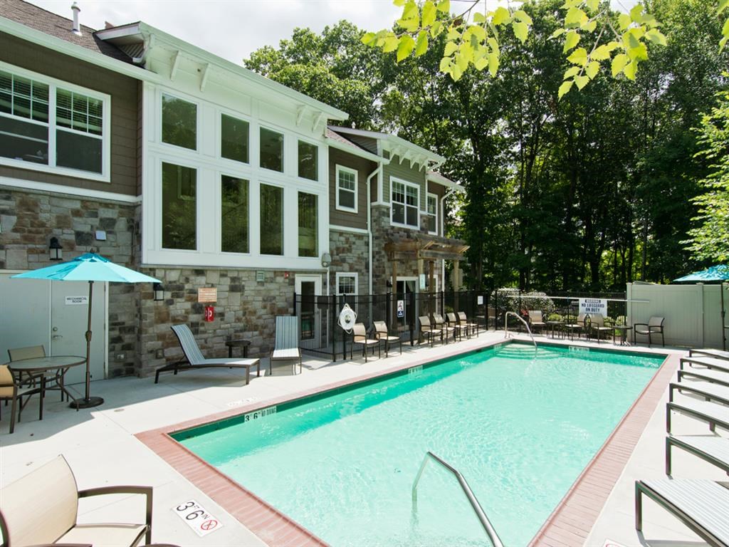 a swimming pool in front of a house with a resort style pool