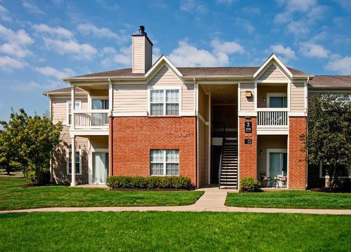 Two-story apartment building with green lawn and trees