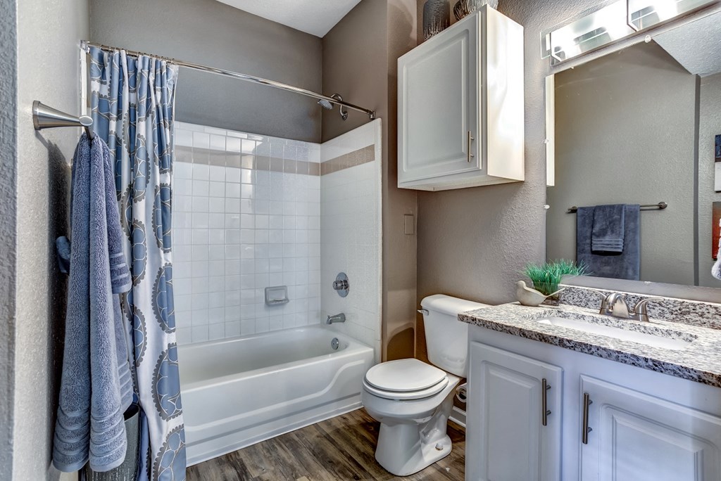Upgraded model bathroom with tile tub and shower and granite countertops