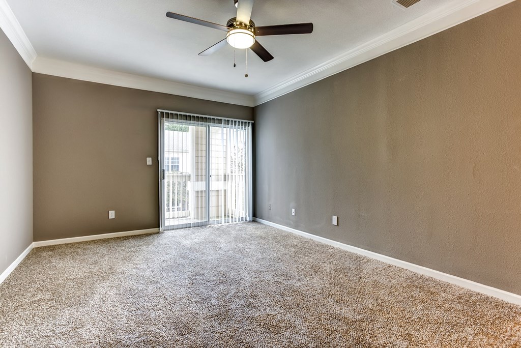 Upgraded living area with crown molding, carpet, and sliding glass door that leads to balcony