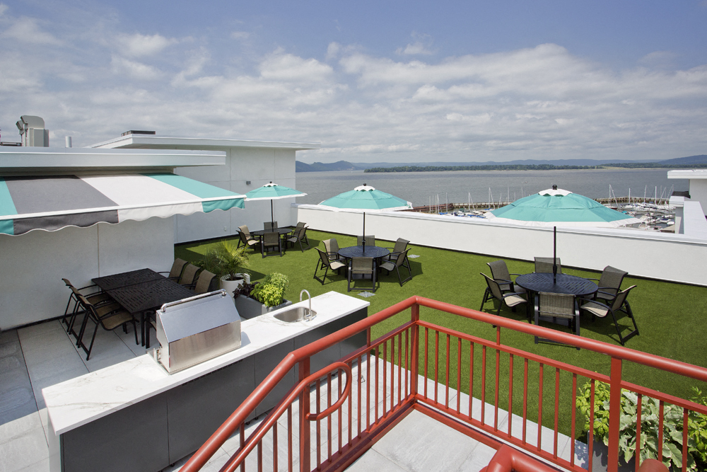 a rooftop terrace with tables and umbrellas and a view of the water