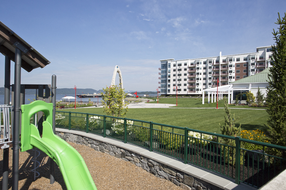 a playground with a green slide in a park next to a building