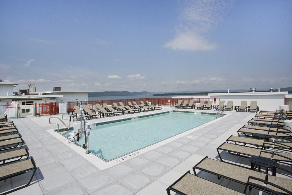 a swimming pool on the roof of a building with lounge chairs