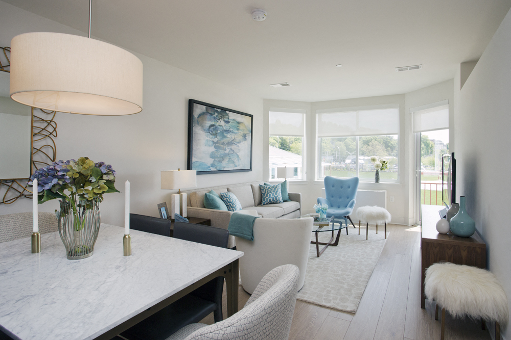 the living room and dining room of a house with white walls and a white table