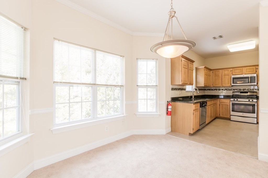 an empty kitchen with wood cabinets and a large window