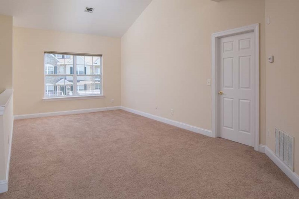 an empty room with a white door and a window