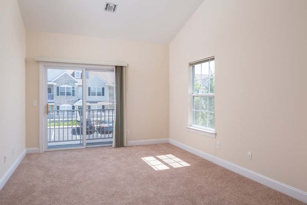 an empty living room with a sliding glass door to a balcony