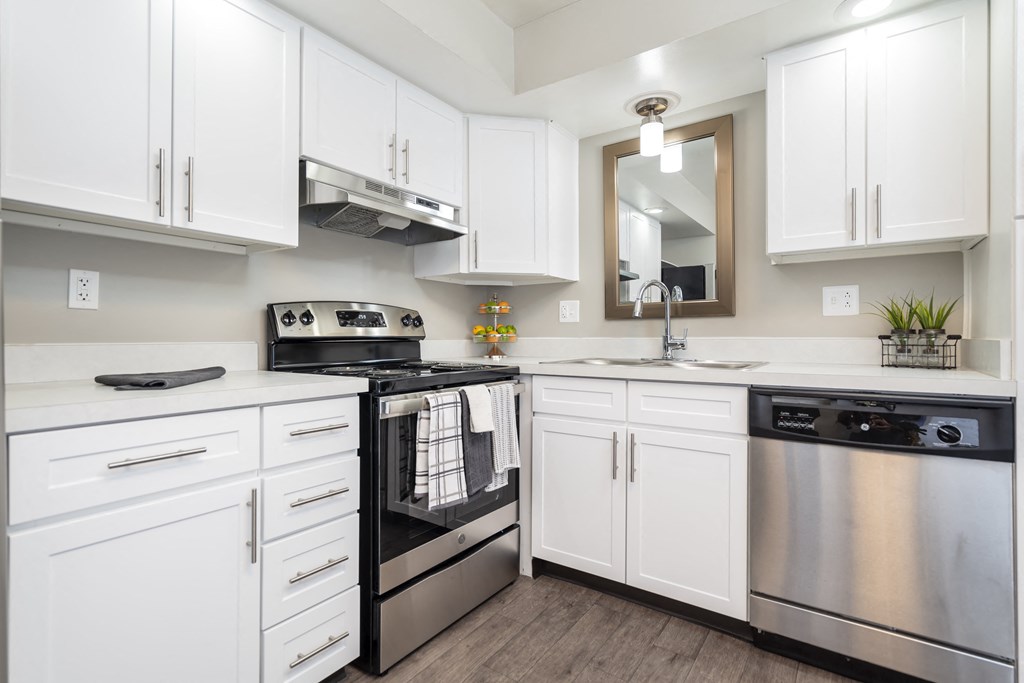 a white kitchen with stainless steel appliances and white cabinets