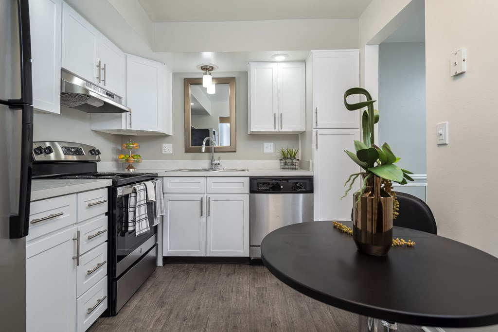 a kitchen with white cabinets and stainless steel appliances and a black table