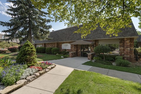 the front of a brick house with a sidewalk and trees